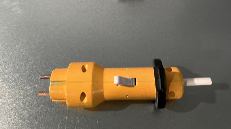 orangener Stecker mit einem Schalter, der das ausstecken mit nur einer Hand erleichtert.