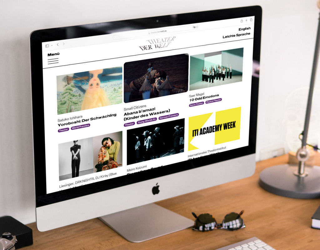 Ein iMac steht auf einem Schreibtisch. Auf seinem Bildschirm ist die Startseite von „Theater der Welt 2023“ zu sehen.